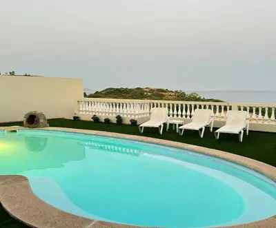 a swimming pool with chairs and the ocean in the background at Sea View Suite with Balcony and Pool - Praia da Luz in Luz