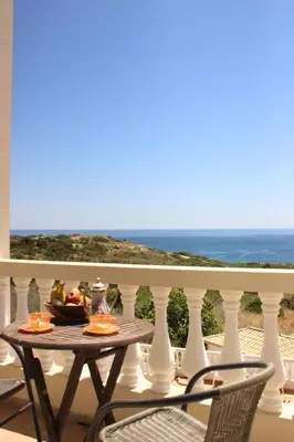 a table on a balcony with a view of the ocean at Sea View Suite with Balcony and Pool - Praia da Luz in Luz