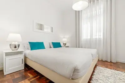 a white bedroom with a large bed with blue pillows at Live, Love and Laugh in Funchal