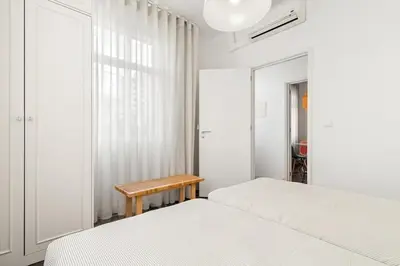 a white bedroom with two beds and a table at Live, Love and Laugh in Funchal