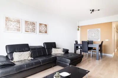 a living room with a black leather couch and a table at GuestReady - Caniço paradise with ocean view in Santa Cruz