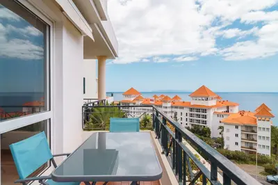 a balcony with a table and chairs and a view of the ocean at GuestReady - Caniço paradise with ocean view in Santa Cruz