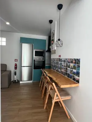 a kitchen with a wooden table and a refrigerator at Casa do Ribeirinho in Machico