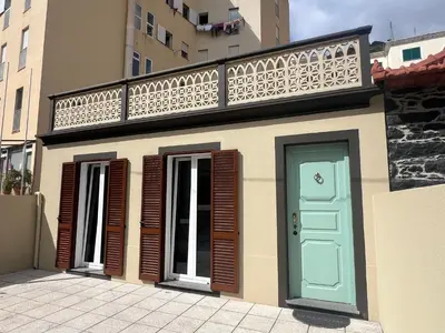 a small building with a balcony and a blue door at Casa do Ribeirinho in Machico