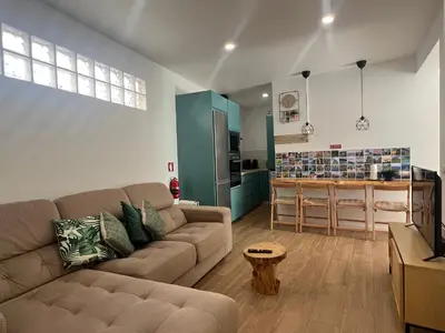 a living room with a couch and a kitchen at Casa do Ribeirinho in Machico