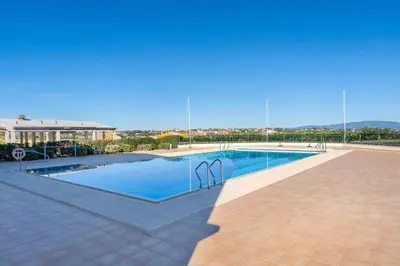 a large swimming pool with blue water in a courtyard at Casa Júlia, golfe piscina e praia in Lagos