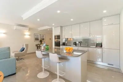 a kitchen with white cabinets and a counter with chairs at Casa Júlia, golfe piscina e praia in Lagos