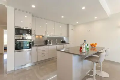 a kitchen with white cabinets and a table and chairs at Casa Júlia, golfe piscina e praia in Lagos