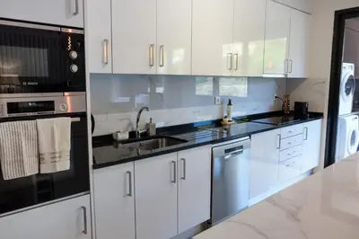 a kitchen with white cabinets and black counter tops at New 3 Bedroom Luxury Family Apartment - Airco, King Size Beds, Fully equipped kitchen, Balcony, Washingmachine, 2 bathrooms, Free parking, Fast Internet, 142m2 in Machico
