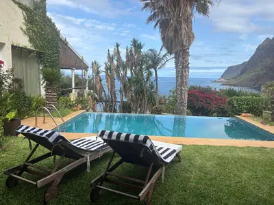 two chairs sitting next to a swimming pool at Suite Bela Vigia 4 in Jardim do Mar