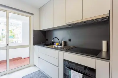 a kitchen with white cabinets and a sink at JMF Apartment in Funchal
