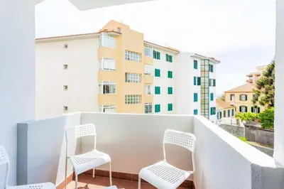 two white chairs sitting on a balcony with buildings at JMF Apartment in Funchal