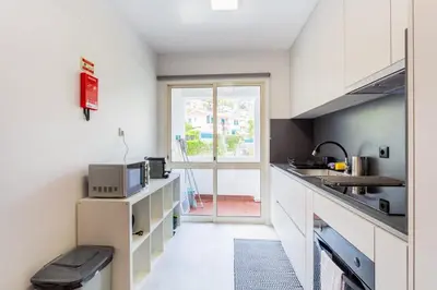 a kitchen with white cabinets and a large window at JMF Apartment in Funchal