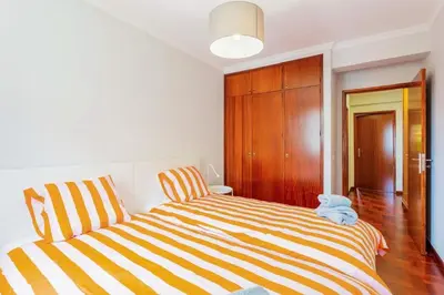 a bedroom with a striped bed and a closet at JMF Apartment in Funchal