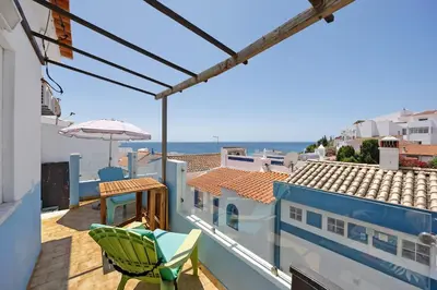 a balcony with a green chair and an umbrella at Casa Dos Netos in Burgau