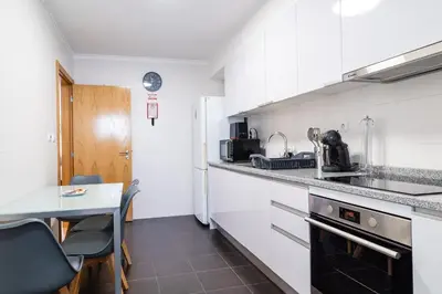 a kitchen with white cabinets and a table and chairs at GuestReady - Duplex paradise in Caniço in Caniço