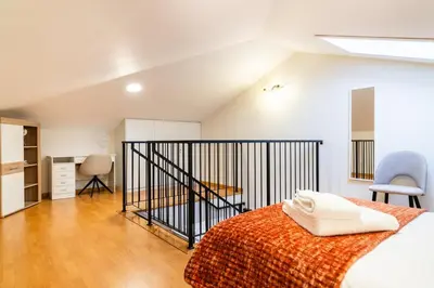 a bedroom with a bed and a staircase with chairs at GuestReady - Duplex paradise in Caniço in Caniço