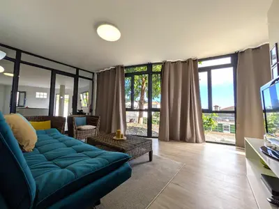 a living room with a blue couch and a tv at Monte Gordo Accommodation in Ribeira Brava