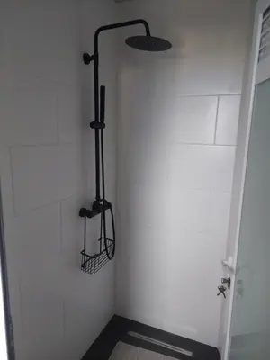 a shower in a bathroom with a white wall at Monte Gordo Accommodation in Ribeira Brava