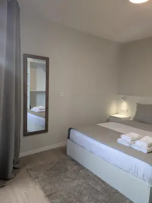 a white bedroom with a bed and a mirror at Monte Gordo Accommodation in Ribeira Brava