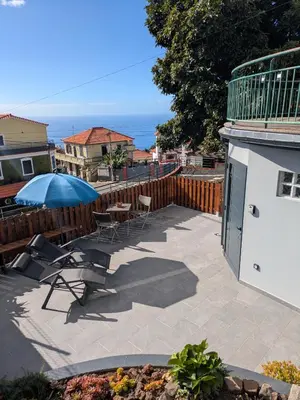 a patio with chairs and a table and an umbrella at Monte Gordo Accommodation in Ribeira Brava