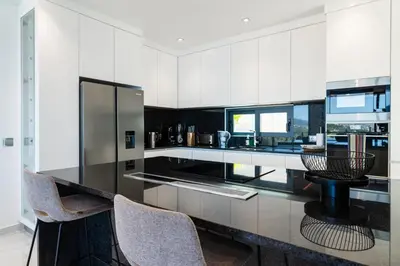 a kitchen with a black counter top and chairs at GuestReady - Sunset Heaven Villa in Calheta