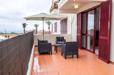 a patio with chairs and an umbrella on a balcony at R&V Paradise by GALMI in Santa Cruz