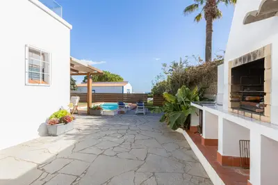 a backyard with a stone patio with a fireplace at Luz Home - Three Bedroom Villa in Luz
