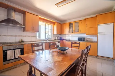 a kitchen with a wooden table with chairs and a refrigerator at Casa das Lajes by LovelyStay in Gaula