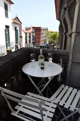 a white table and chairs on a balcony with a bottle of wine at Zarco Suites by Sé Funchal in Funchal