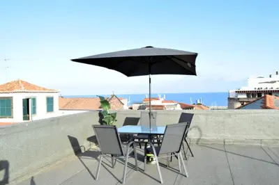 a table and chairs with an umbrella on a roof at Zarco Suites by Sé Funchal in Funchal