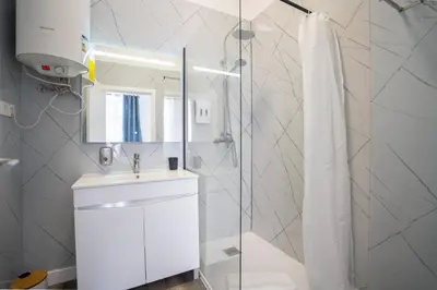 a white bathroom with a sink and a shower at Zarco Suites by Sé Funchal in Funchal