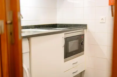 a white kitchen with a microwave and a sink at Lido Escape in Funchal