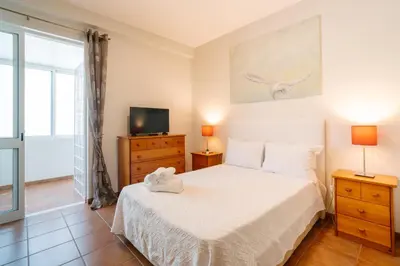 a bedroom with a white bed and a tv at Lido Escape in Funchal