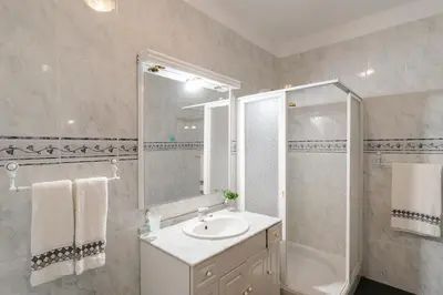 a white bathroom with a sink and a shower at Casa Carreiro in Paul do Mar