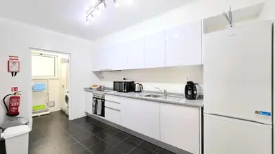 a white kitchen with a sink and a refrigerator at Casa Dama Ana in Caniço