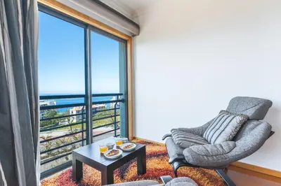 a living room with a chair and a large window at Views of Madeira by Atlantic Holiday in Ilhéu do Gorgulho