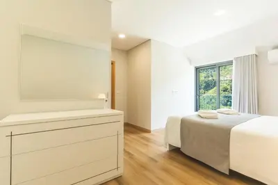 a white bedroom with a bed and a mirror at Villa Lorenzo by Atlantic Holiday in São Vicente