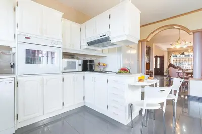 a kitchen with white cabinets and a table and chairs at Villa Mar by Atlantic Holiday in Porto Moniz