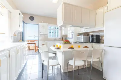 a kitchen with white cabinets and a white table and chairs at Villa Mar by Atlantic Holiday in Porto Moniz