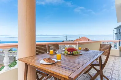 a wooden table with a plate of food on a balcony at Villa Mar by Atlantic Holiday in Porto Moniz