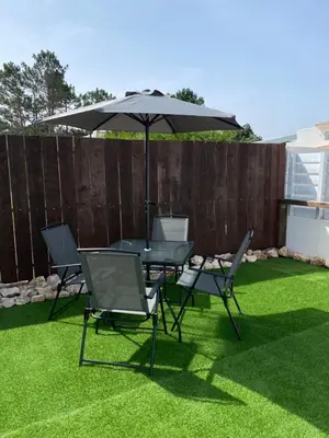 a table and chairs with an umbrella on the grass at Casa Vinny in Aljezur