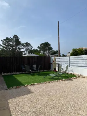 a backyard with a lawn with chairs and a fence at Casa Vinny in Aljezur
