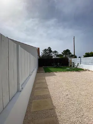 a long white wall next to a fence at Casa Vinny in Aljezur