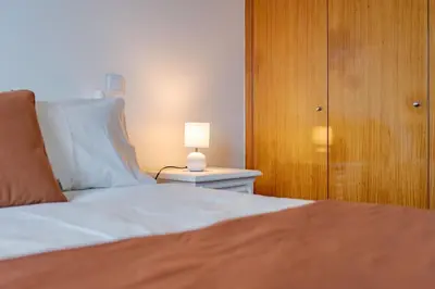 a bedroom with a bed with a lamp on a night stand at atlantico view in Caniço