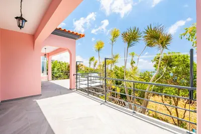 a balcony with a view of the ocean and palm trees at Amendoeira Residence by Homie in Ponta do Sol