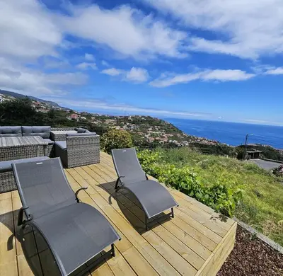 two chairs sitting on a wooden deck with the ocean at Moradia em Ponta do Sol 2 Quartos in Ponta do Sol