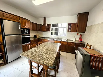 a kitchen with a table and a stainless steel refrigerator at Moradia em Ponta do Sol 2 Quartos in Ponta do Sol