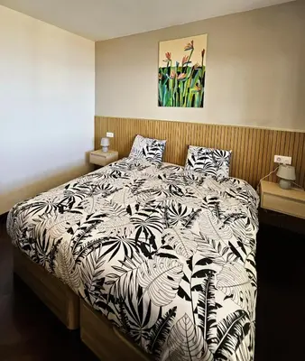 a bedroom with a bed with a black and white comforter at Moradia em Ponta do Sol 2 Quartos in Ponta do Sol