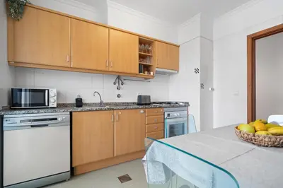 a kitchen with wooden cabinets and a table with a bowl of fruit at Madalenas Holiday Retreat - Free Parking in Funchal in Funchal